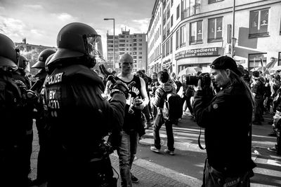 Crowd walking on street by buildings at may day