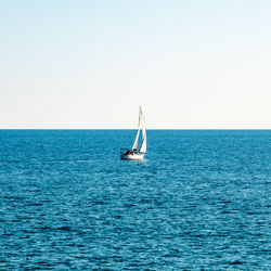 Sailboat sailing on sea against clear sky