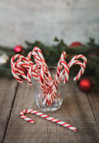 Close up of glass full of candy canes against christmas backdrop.