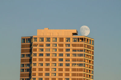 Low angle view of modern building against clear sky with full moon