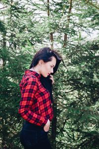 Side view of young woman looking away while standing in forest