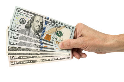 Close-up of hand holding paper over white background