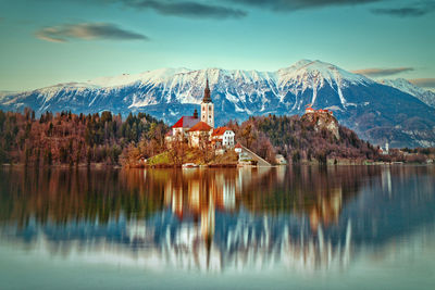 Scenic view of lake by snowcapped mountains against sky