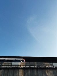 Low angle view of bridge against buildings against clear blue sky