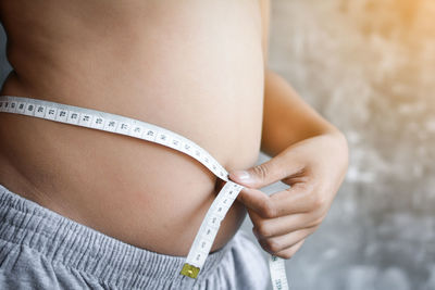 Midsection of woman checking waist with tape measure