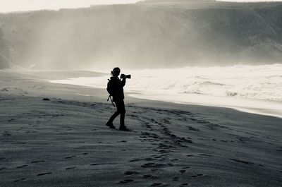 Full length of man photographing on beach