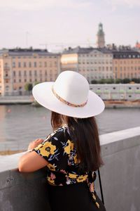 Rear view of woman standing by river in city