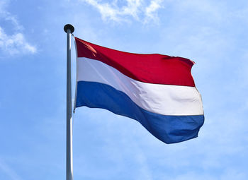 Low angle view of dutch flag waving against blue sky