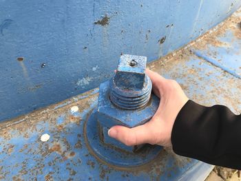 Cropped hand holding rusty blue metal