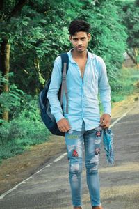 Portrait of young man standing against trees