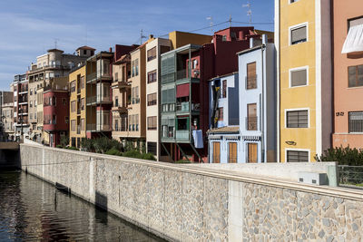 Residential buildings by canal against sky