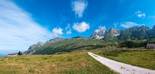 Scenic view of road by mountains against blue sky