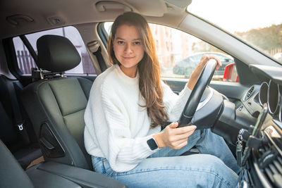 Portrait of young woman using phone while sitting in car