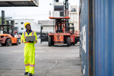 Engineer using laptop while analyzing cargo containers at harbor