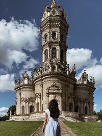 Rear view of woman visiting building against sky