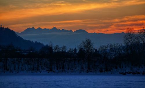 Scenic view of snow covered mountains against orange sky