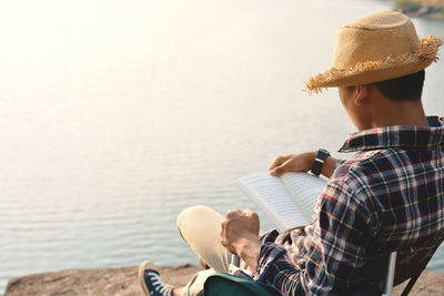 Man reading book at lakeshore