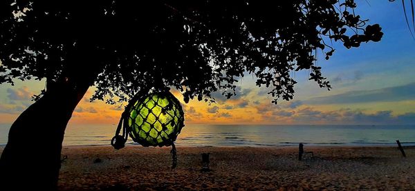 Silhouette tree by sea against sky during sunset