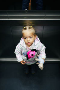 Portrait of cute baby girl sitting on escalator