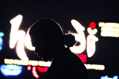 Close-up portrait of silhouette woman with illuminated lights at night