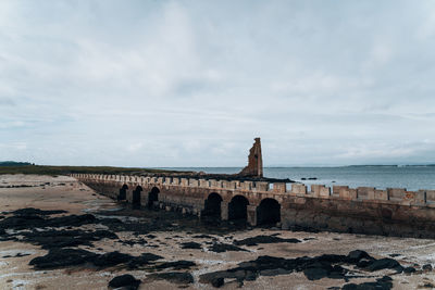 Scenic view of bridge and ruin by the sea against sky