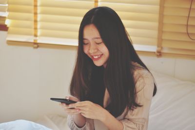 Beautiful young woman using mobile phone at home