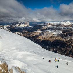 Group of people on snowcapped mountain against sky