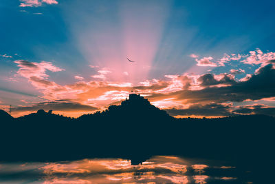 Silhouette mountain at waterfront against sky during sunset