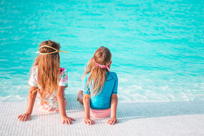 Rear view of women sitting in swimming pool