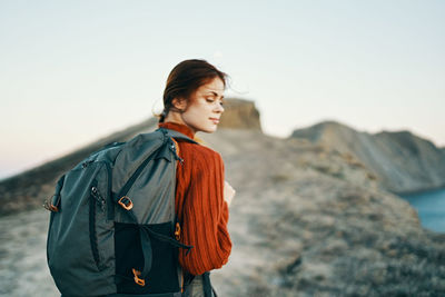 Young woman looking away against sky