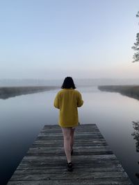 Rear view of woman standing by lake