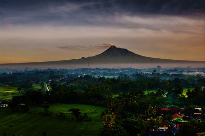 Scenic view of landscape against cloudy sky during sunset