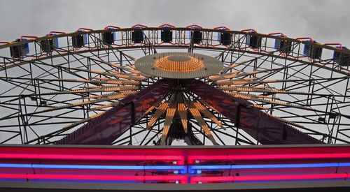 Low angle view of illuminated ferris wheel at dusk