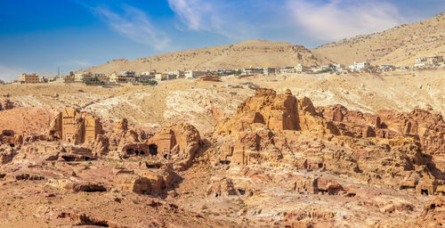 View to the ancient nabataean moghar annasara tombs with wadi musa town in background, petra, jordan