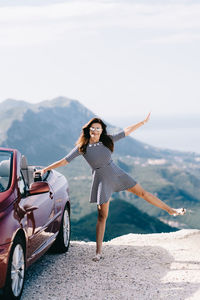 Woman with umbrella standing on mountain road