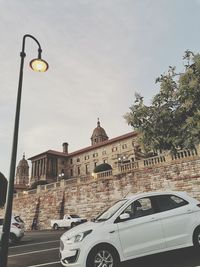 Low angle view of street light by building against sky