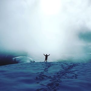 Man in sea against sky during winter