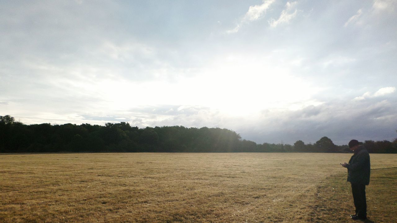 lifestyles, leisure activity, sky, men, standing, person, full length, cloud - sky, rear view, sunlight, walking, nature, tranquility, tree, tranquil scene, casual clothing, scenics