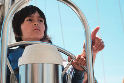 Close-up of boy holding steering wheel while traveling in sailboat