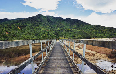 Bridge over mountain against sky