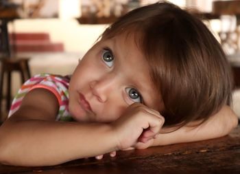 Cute girl looking away while leaning on table