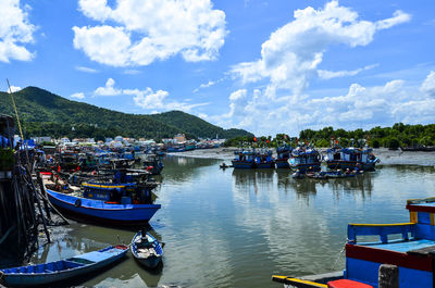 Boats moored at harbor against sky