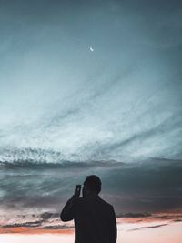 Rear view of silhouette man against sky during sunset