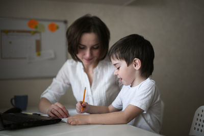 Tutor deals with the preschooler with a laptop, a real home interior, the concept of childhood