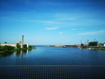 Scenic view of river by buildings against sky