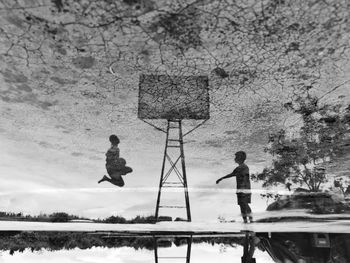 People standing by tree against sky