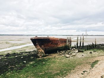 Abandoned boat on beach against sky