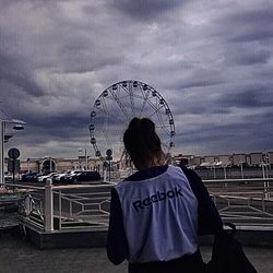 Rear view of woman with ferris wheel against sky