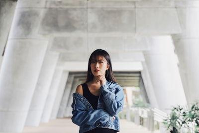 Portrait of young woman standing in corridor against ceiling