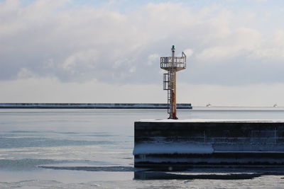 Lighthouse by sea against sky